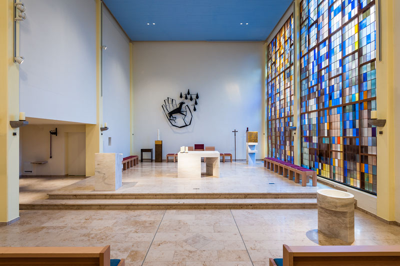 Frontalansicht des Altarbereichs mit farbigem Glasfenstern auf der rechten Seite